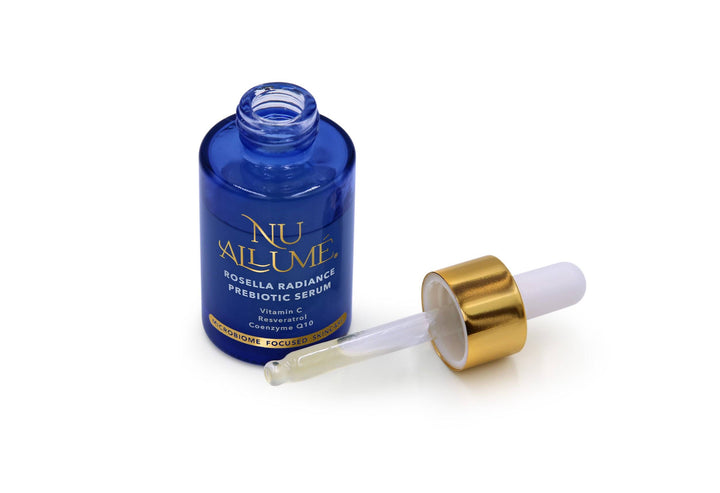 An open bottle of Nu Allumé Rosella Radiance Prebiotic Serum with the dropper showing some of the serum in the dropper tube to demonstrate its colour